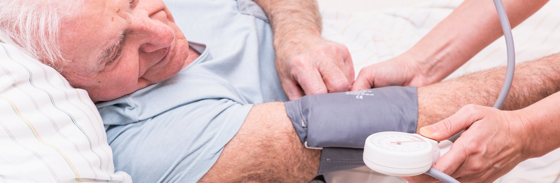 Blutdruckmessen bei älterem Patient im Bett