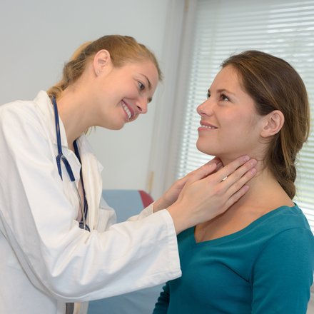 Ärztin untersucht den Hals einer Patientin