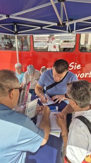 Arzt der Inneren Medizin mit zwei Besuchern am Infostand