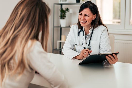 Freundlich lächelnde Ärztin spricht mit Patientin
