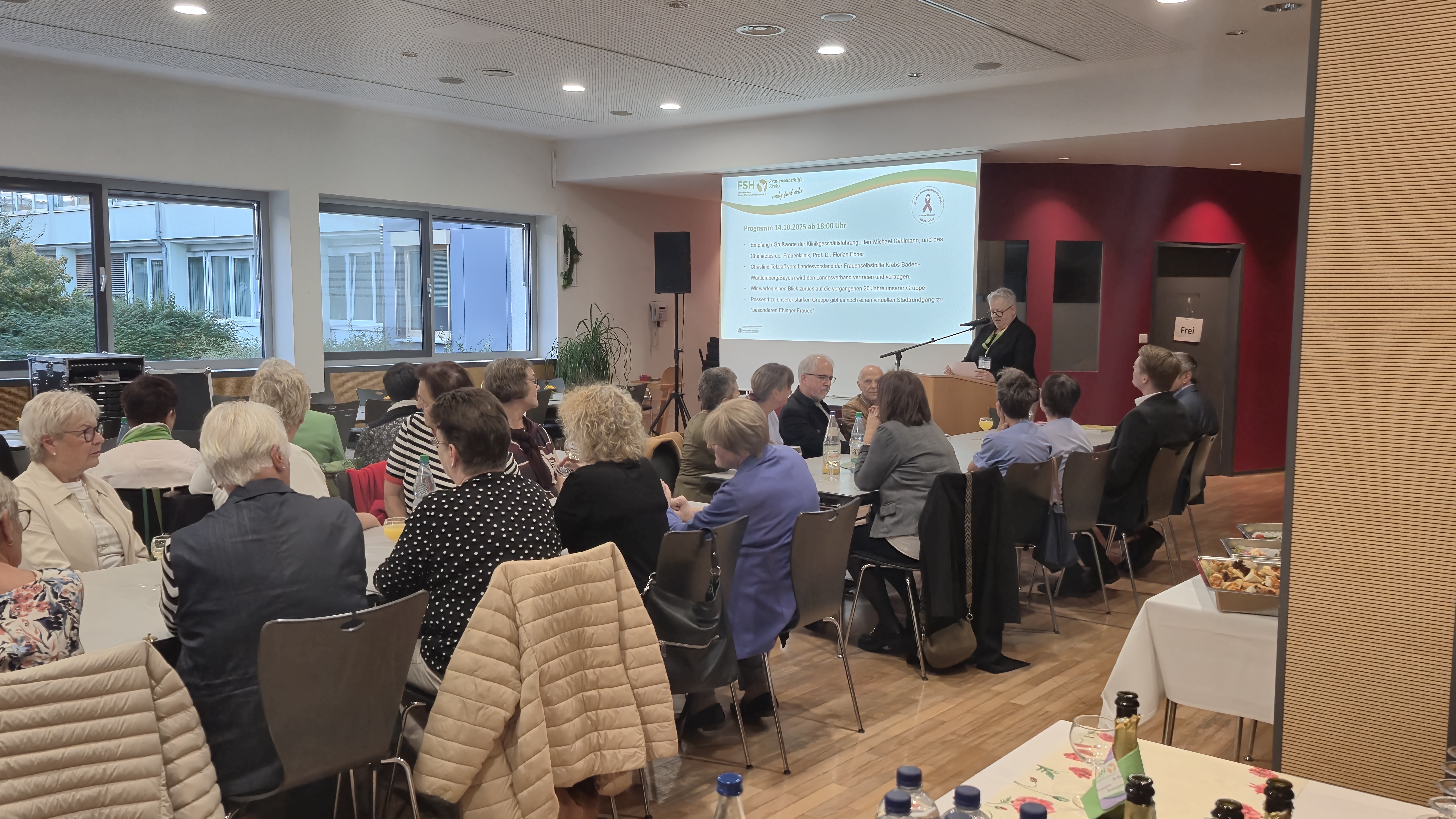 Gefüllter Saal und Rednerin am Rednerpult